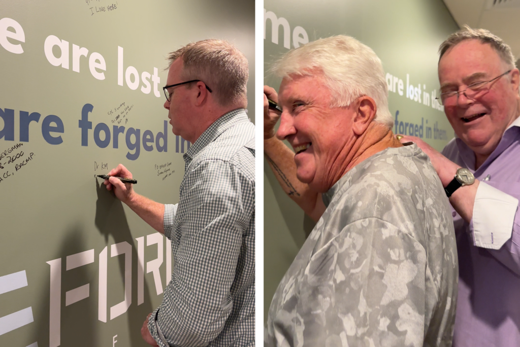 GO2 Medical Director Kieran McCarthy who developed the veteran health care program signing the wall and two patients part of the veteran community who attend GO2 Health signing the wall.