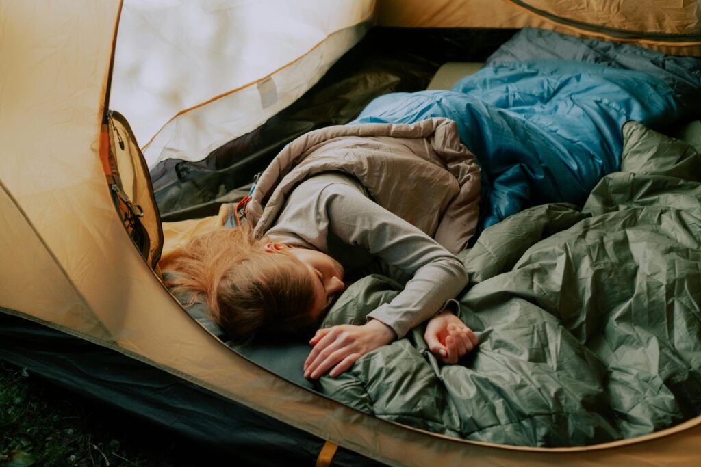 A woman trying to fall asleep while camping in a tent, suffering from sleep disorders.